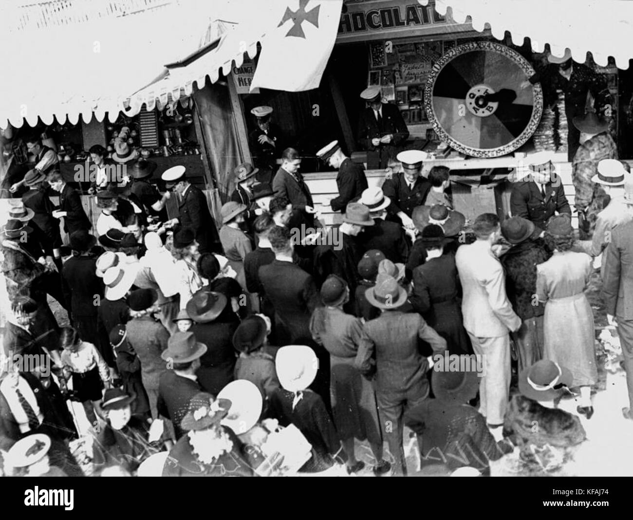 A photograph from the 1938 Exhibition Ground in Brisbane, showing a chocolate wheel at the ambulance stall. This image captures a moment of community engagement during the fair. Stock Photo