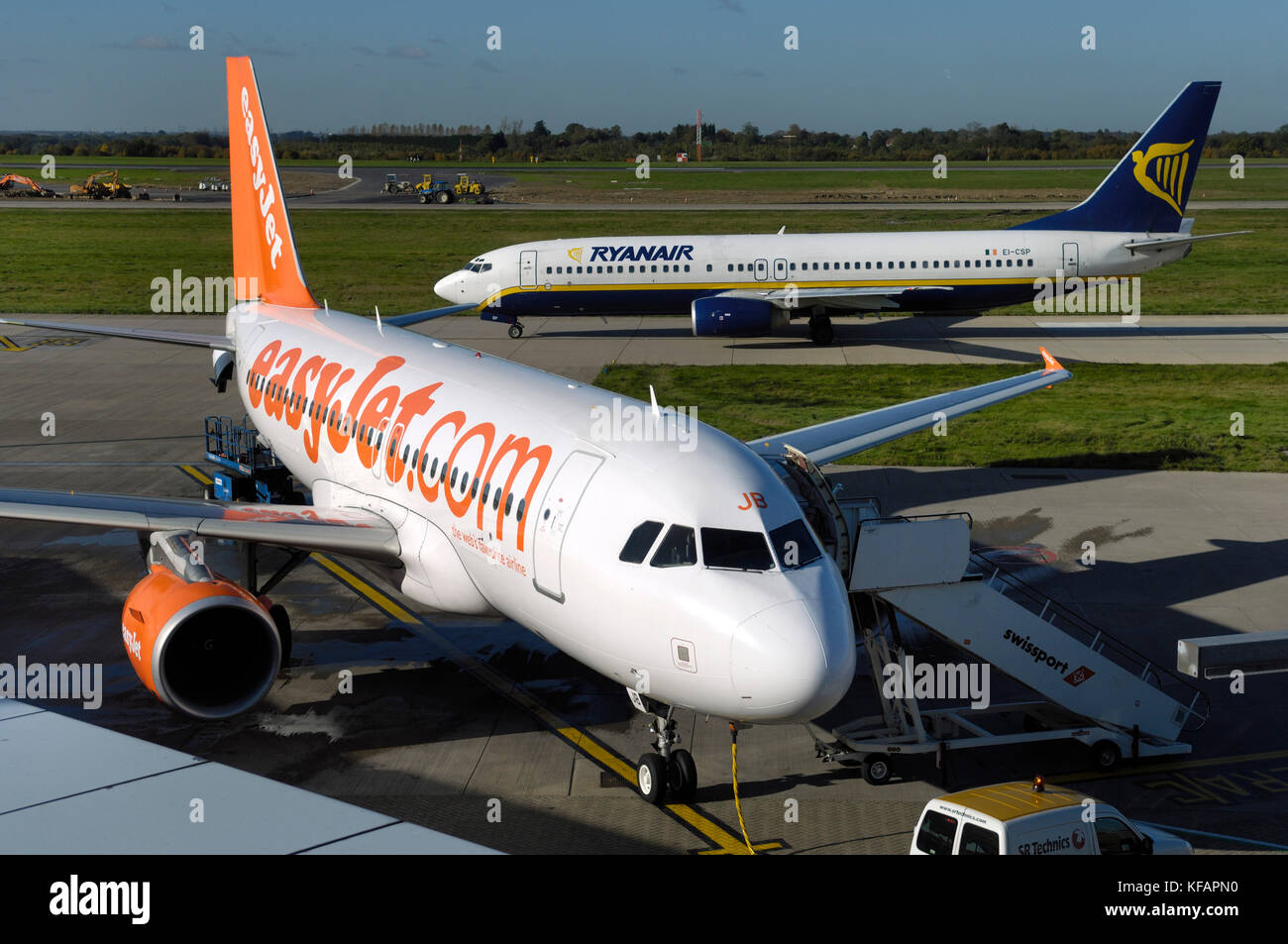 an easyJet Airbus A319-100 with Ryanair Boeing 737-800 taxiing and diggers and construction vehicles behind Stock Photo