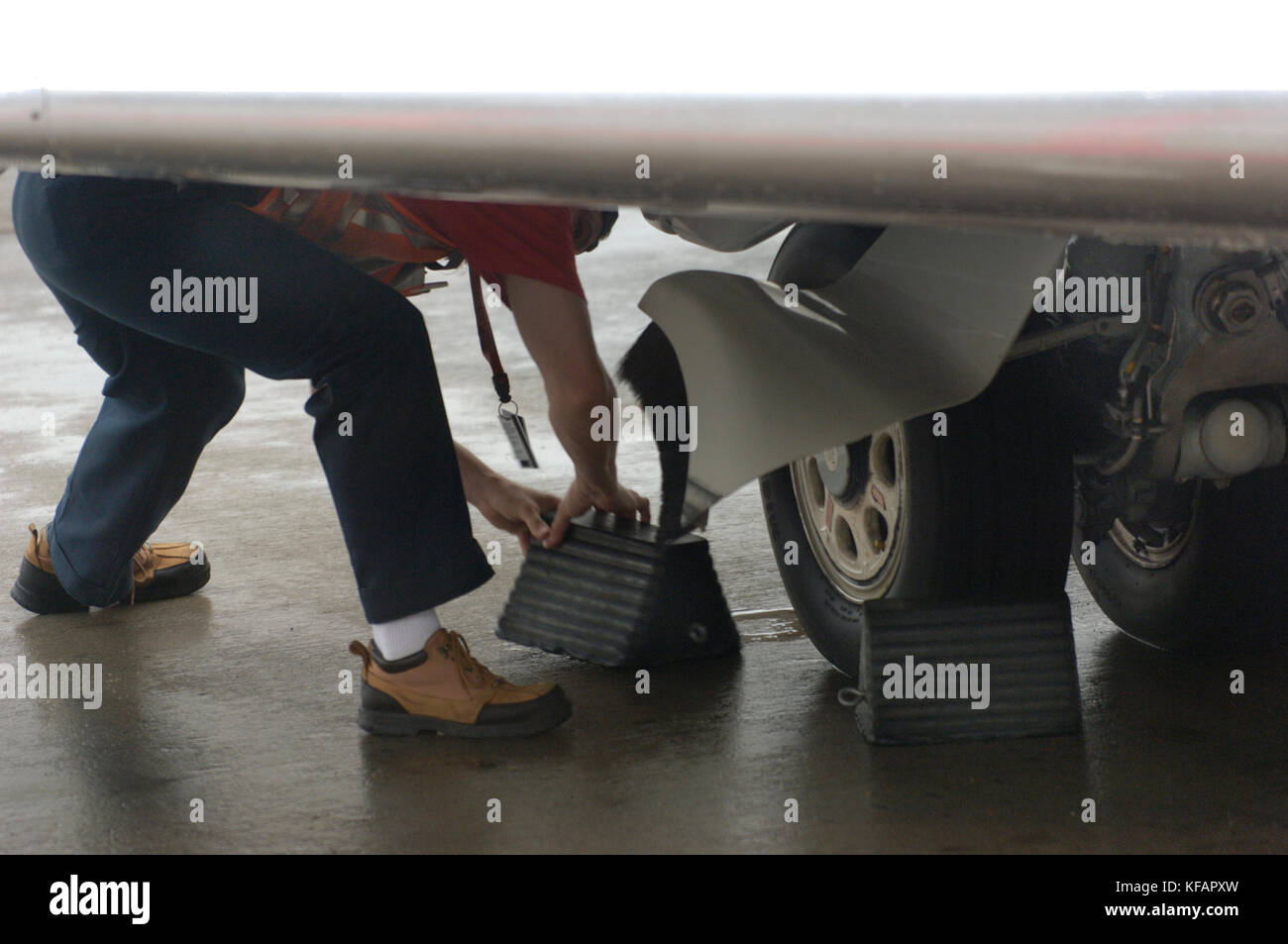 marshaller removing chocks from a Northwest Airlink - Pinnacle Airlines Bombardier CRJ-440 undercarriage parked Stock Photo
