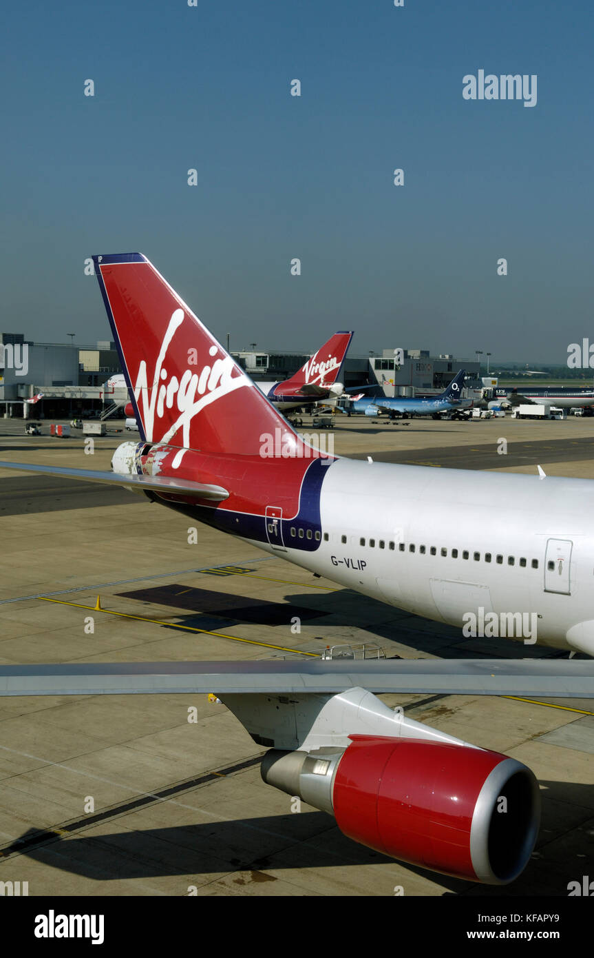 tail and GE CF-6-80C2 jet-engine of a Virgin Atlantic Airways Boeing 747-400 parked with Travel Service 737-800 in O2 special-livery and 747-400 behin Stock Photo