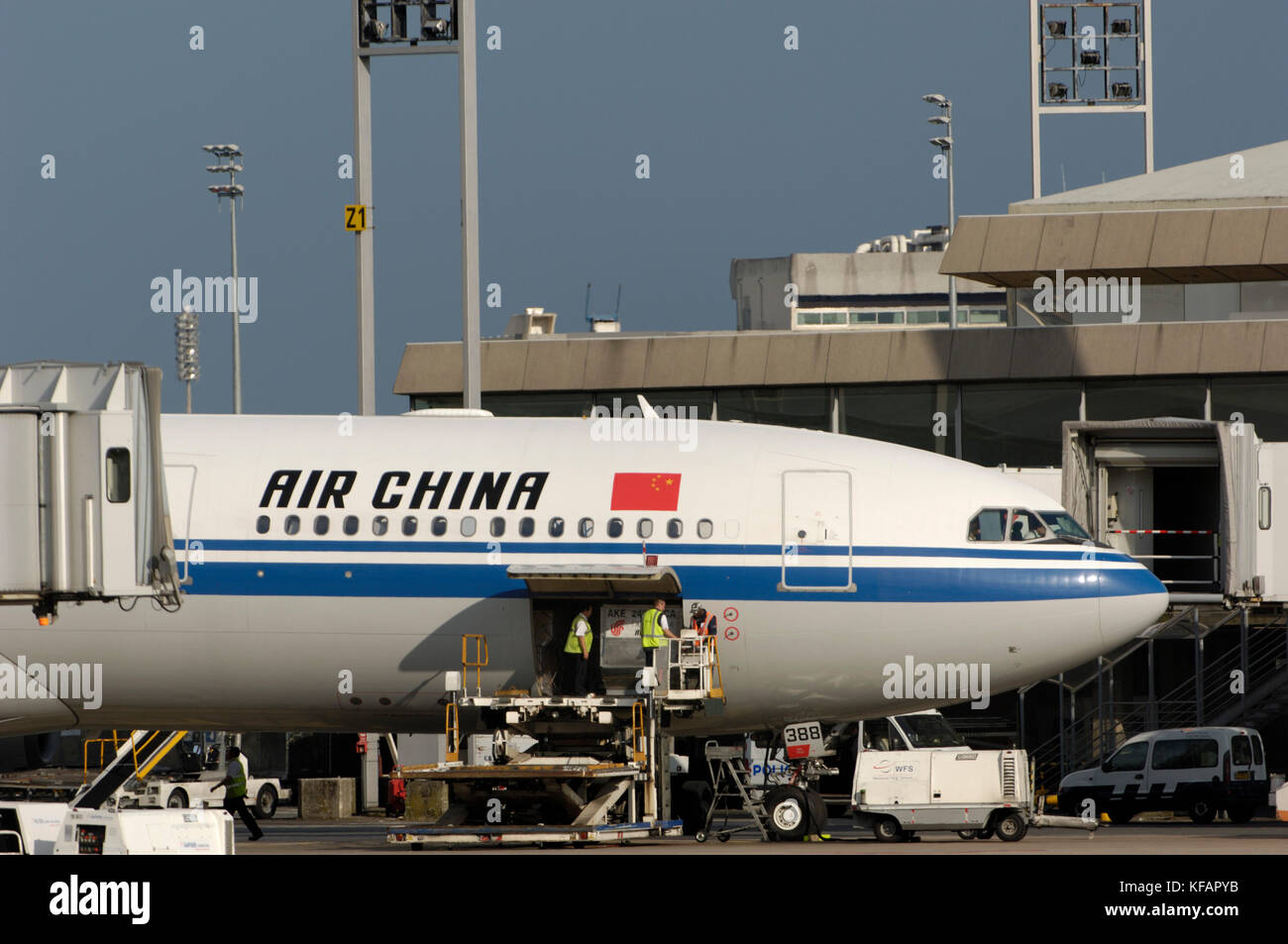 the Air China International CA CCA Airbus A340-313X parked at the terminal with baggage vehicles Stock Photo