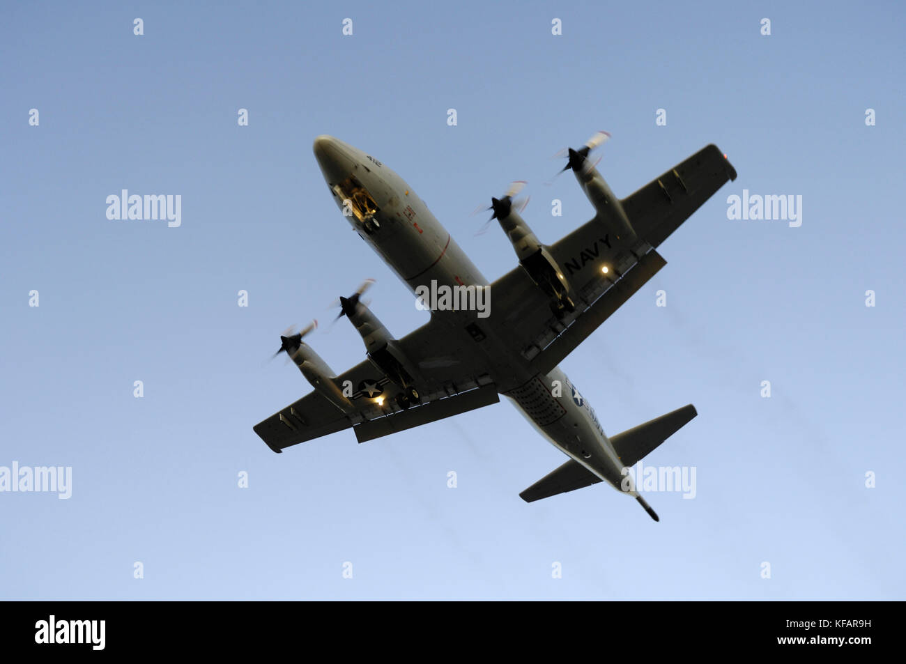 a US Navy Lockheed P-3C Orion on final-approach with black engine-smoke and flaps deployed at dusk Stock Photo
