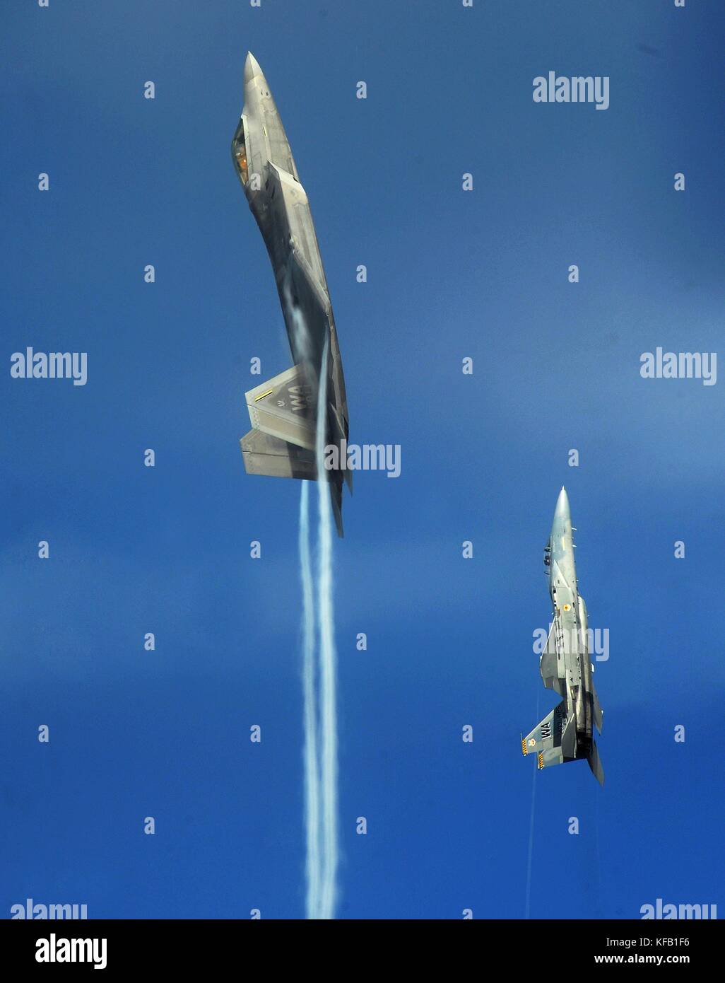 A U.S. Air Force F-22 Raptor stealth tactical fighter aircraft (left) and a U.S. Air Force F-15 Eagle tactical fighter aircraft fly in a vertical climb over the Nellis Air Force Base Nevada Test and Training Range July 16, 2010 near Las Vegas, Nevada.   (photo by Kevin J. Gruenwald via Planetpix) Stock Photo