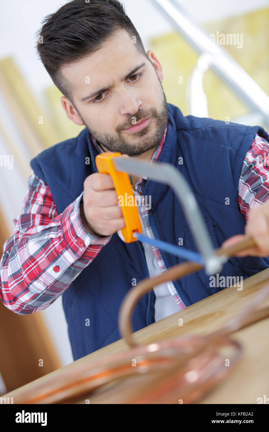 Man trying to cut copper pipe with a hacksaw Stock Photo Alamy