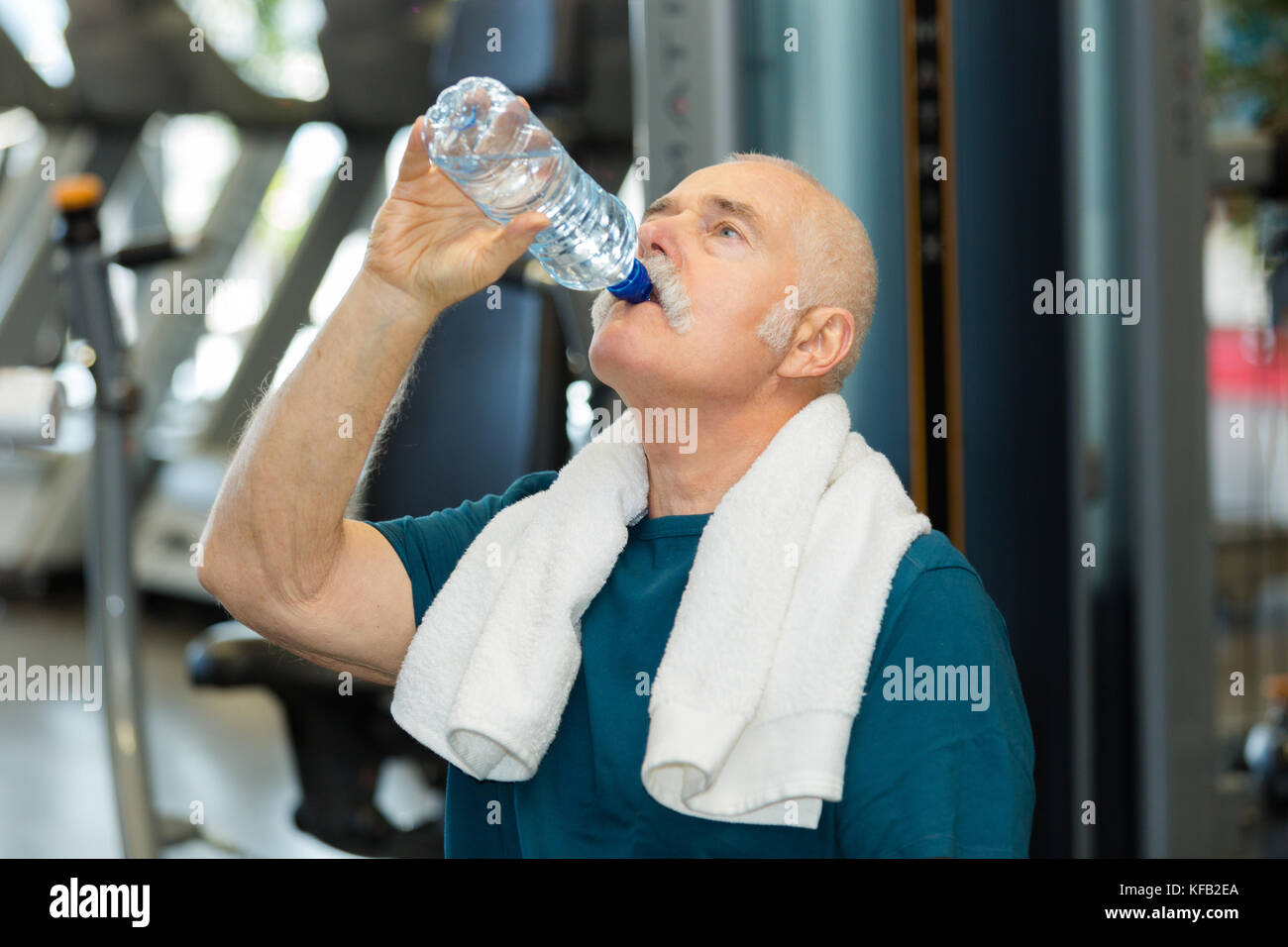 senior man drinking from water bottle in gym room Stock Photo - Alamy