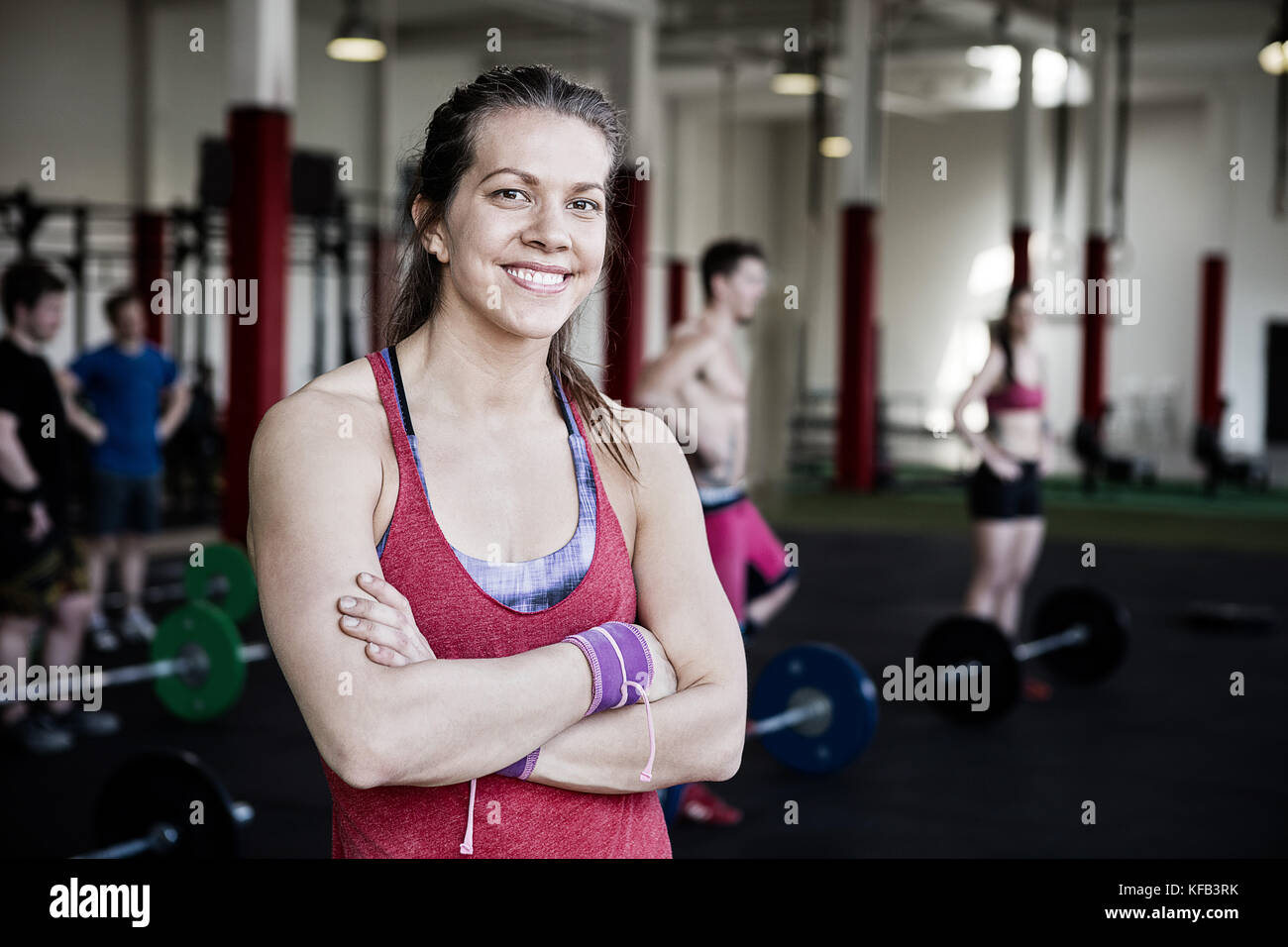 Fit Woman With Arms Crossed Standing In Fitness Center Stock Photo