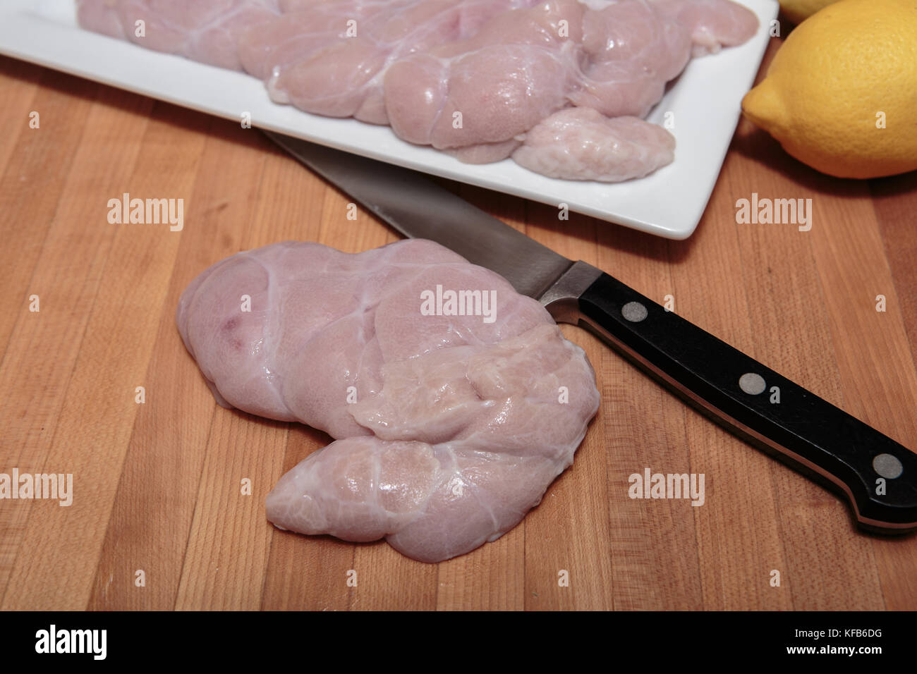 Raw Calfs sweetbreads being prepared in a kitchen on a wooden cutting board Stock Photo