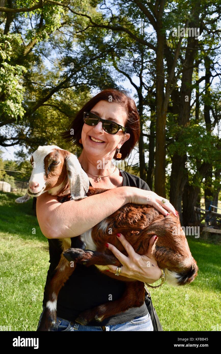 Woman holding baby goat at farm that supplies goats milk to Door County