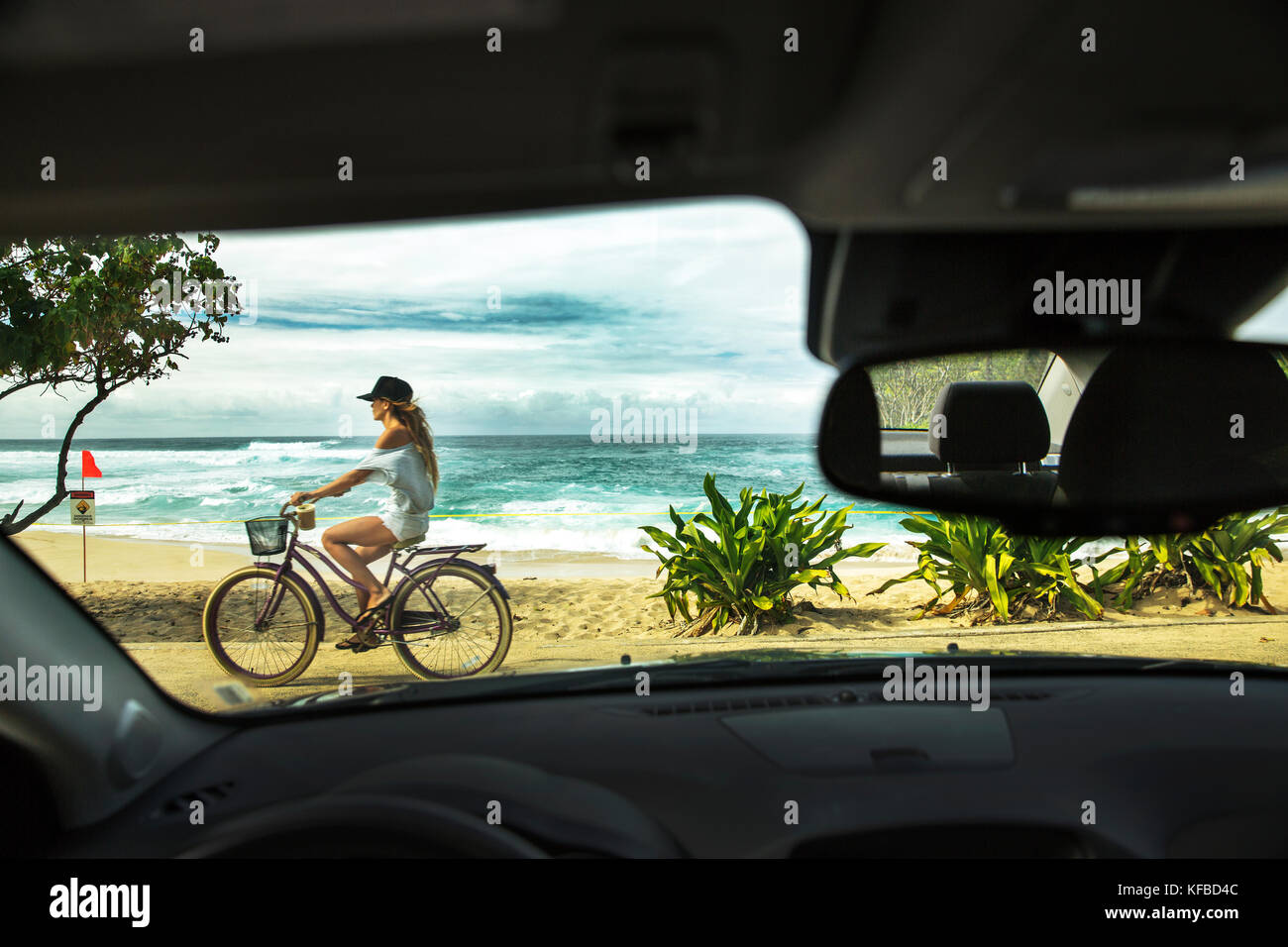 USA, HAWAII, Oahu, Northshore, a young woman riding her bike on the path along Sunset Beach