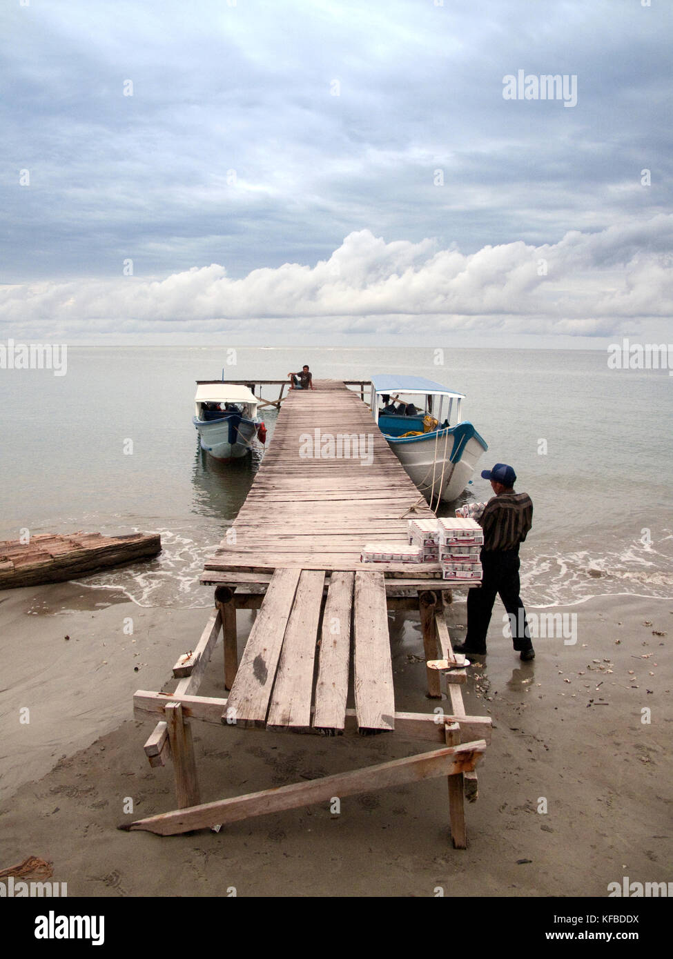 INDONESIA, Mentawai Islands, man carrying supplies to load onto boats at boat dock Stock Photo