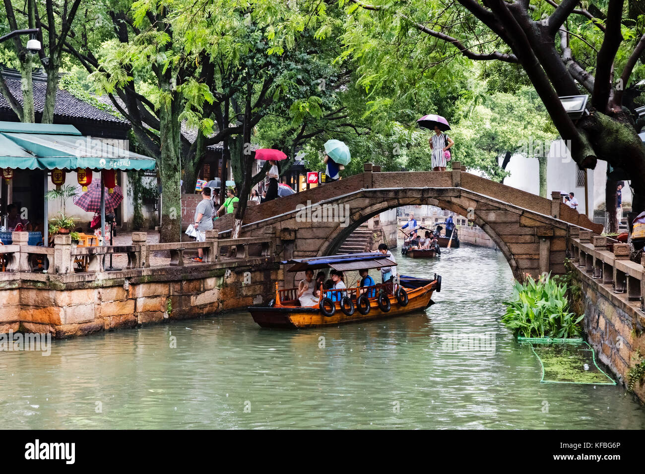 Stock Photo - Tourists ride in row boats in a canal in an ancient town in China, a woman is rowing one of the boat a man is rowing the other Stock Photo