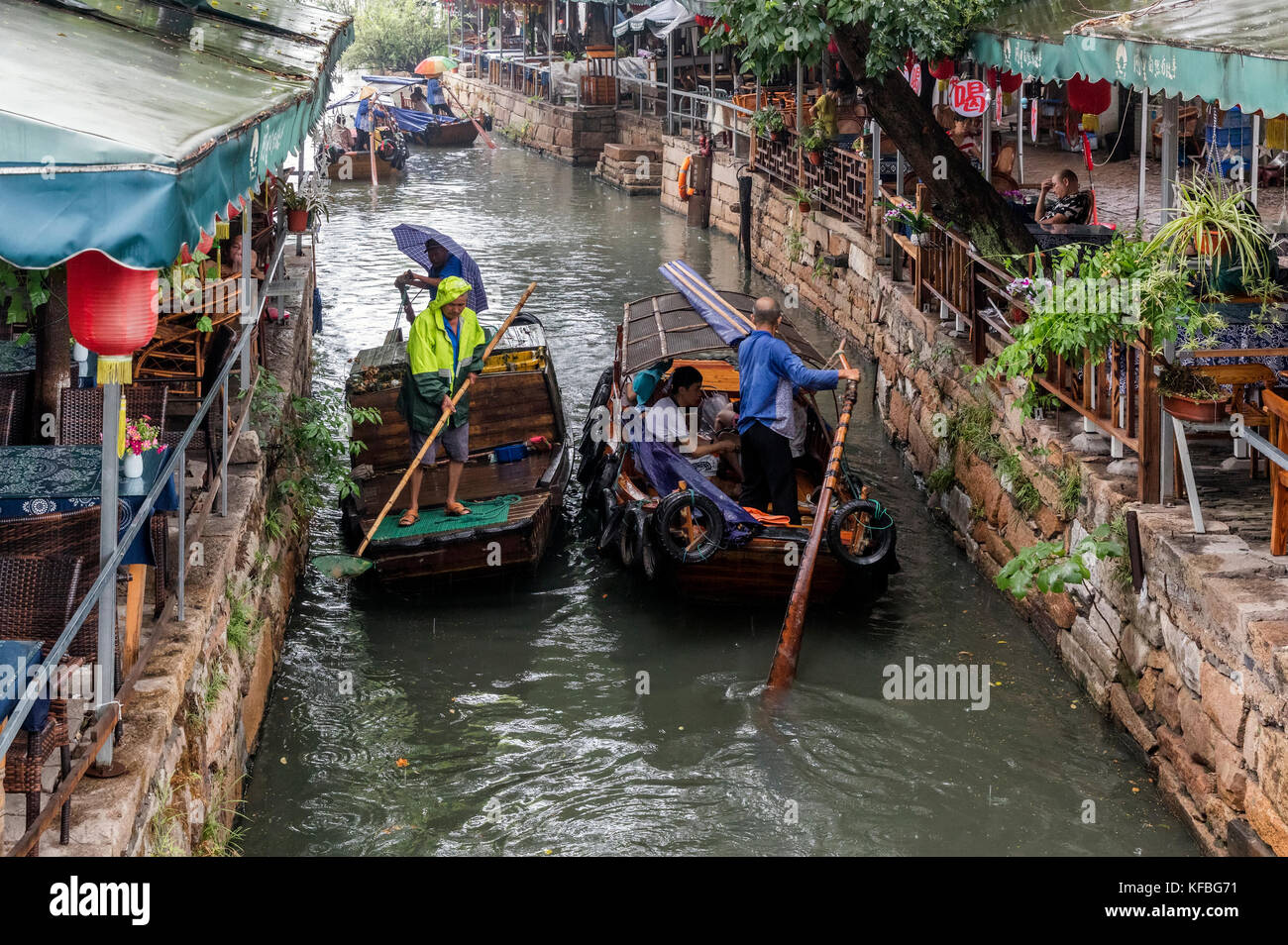 Stock Photo - Tourists ride in row boats in a canal in an ancient town in China, a woman is rowing one of the boat a man is rowing the other Stock Photo