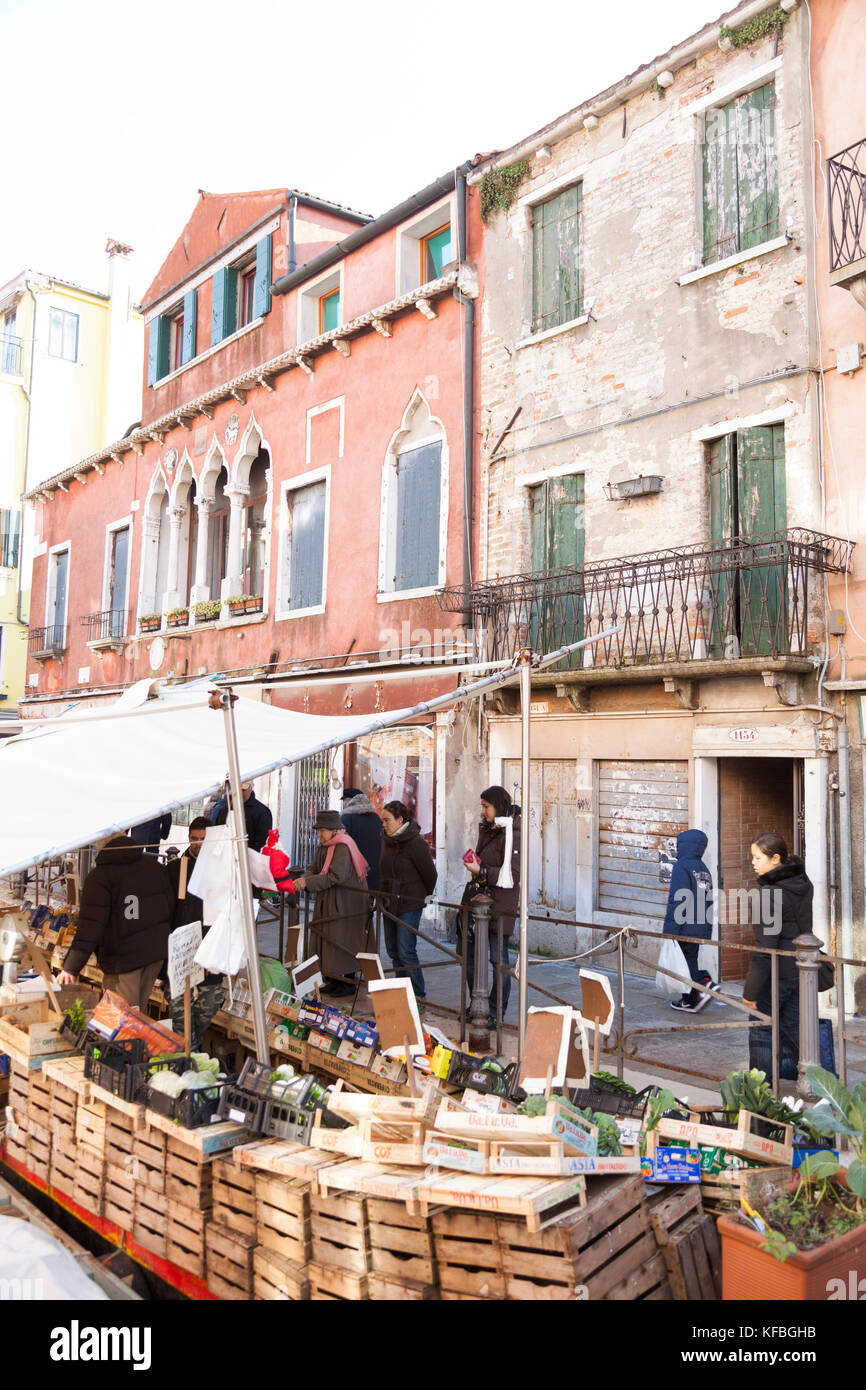ITALY, Venice. Locals shopping at a floating produce market along a canal in the Castello