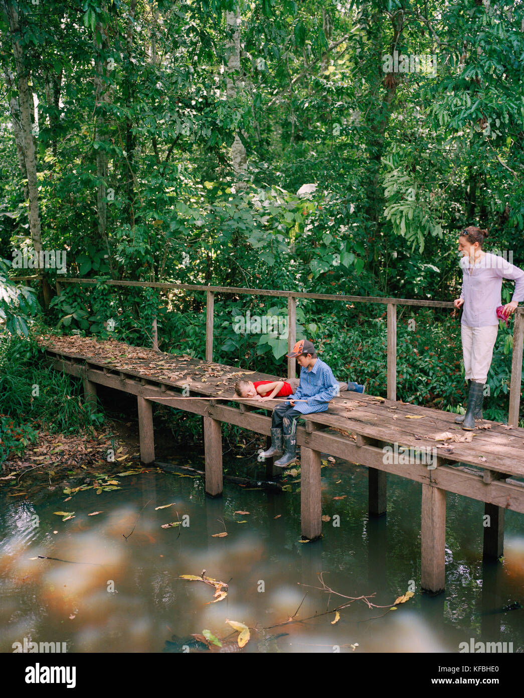 PERU, Amazon Rainforest, South America, Latin America, kids fishing at Tambopata river with mother standing on bridge Stock Photo