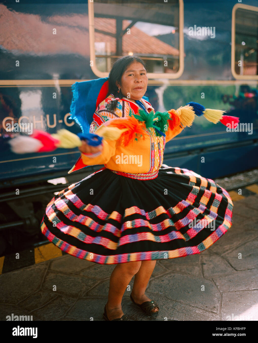 PERU, Cusco, South America, Latin America, mature woman in traditional clothing performing in front of the Hiram Bingham Train. The train travels from Stock Photo