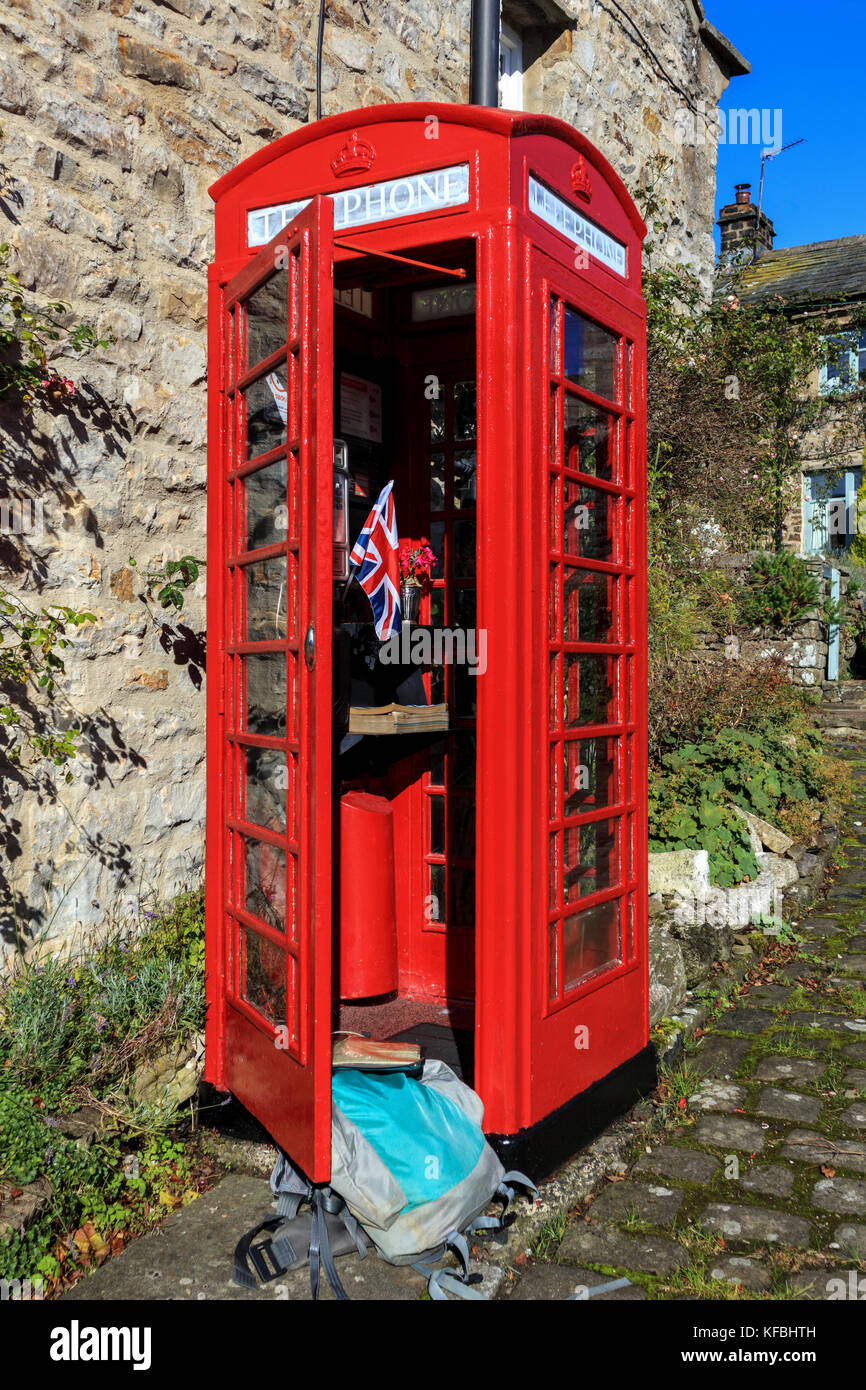A backpack propping open the door of a traditional red British telephone box Stock Photo