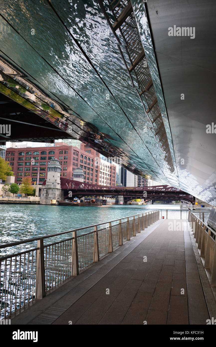 The reflective stainless steel cover protects pedestrians on the Chicago Riverwalk as they pass under the road grates of the N Orleans Street bridge Stock Photo
