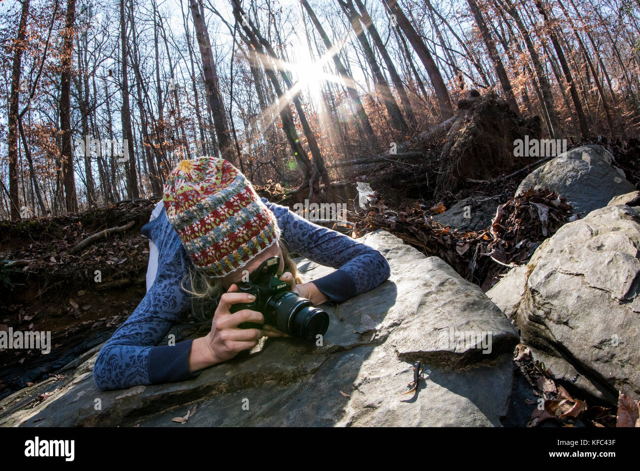 A young woman spends time outdoors with her camera with the sun shining behind her. Stock Photo