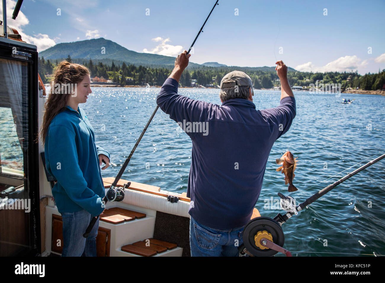 USA, Alaska, Ketchikan, with help from Captain Tony, one woman reels in a fish while fishing the Behm Canal near Clarence Straight, Knudsen Cove along Stock Photo