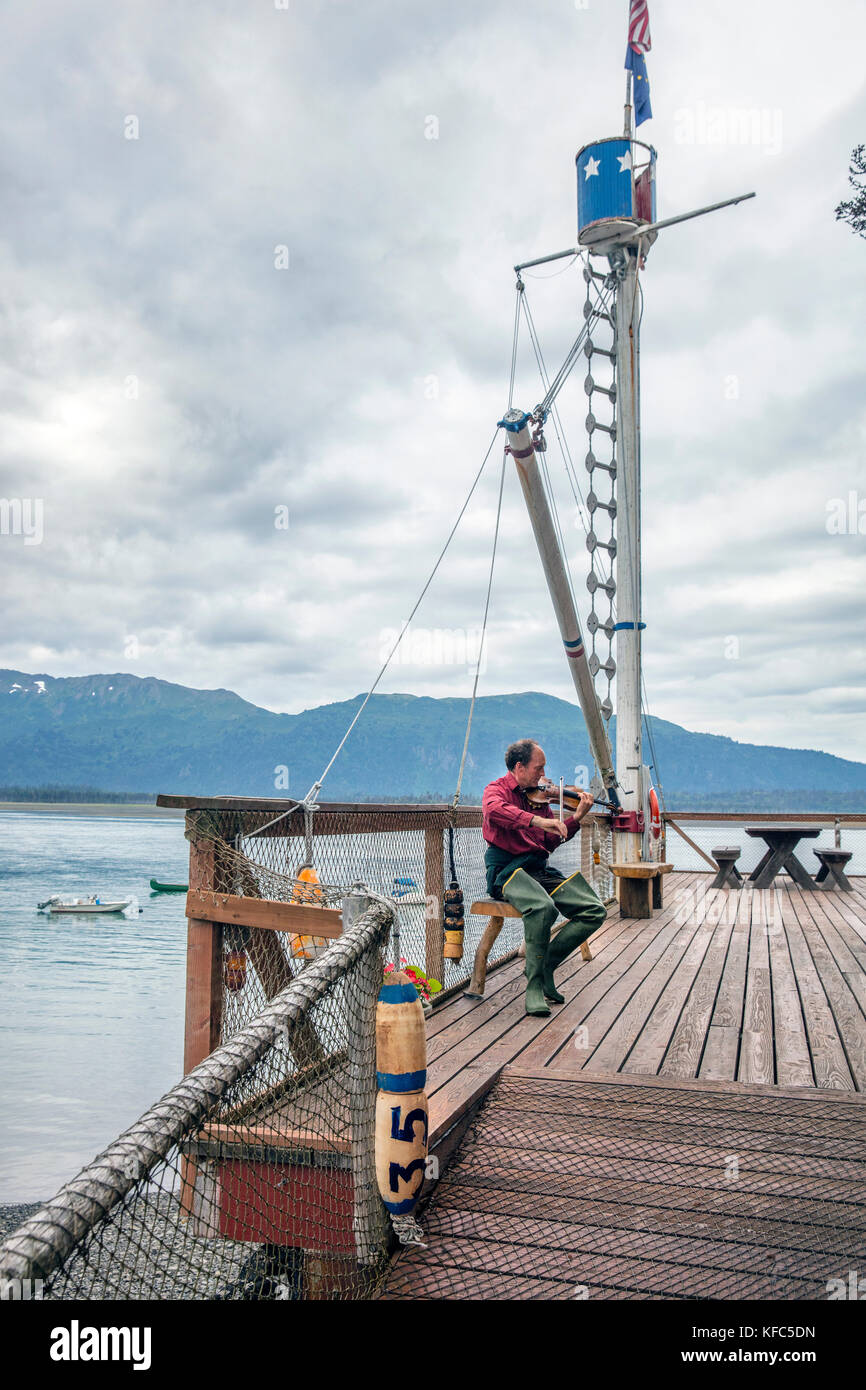 USA, Alaska, Homer, China Poot Bay, Kachemak Bay, one of the employees playing the violin on the dock at Kachemak Bay Wilderness Lodge Stock Photo