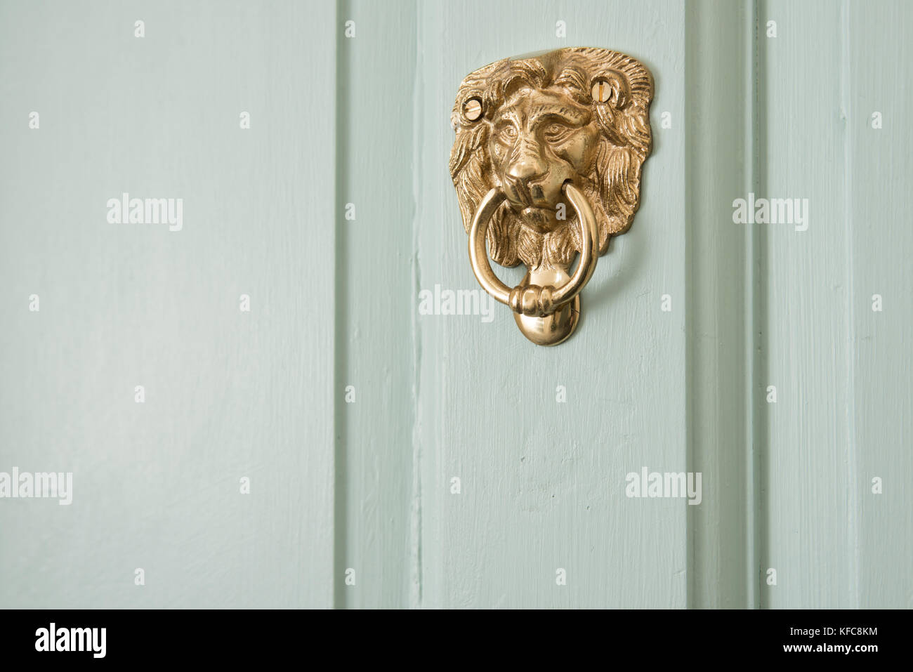 An ornate, brass, lions head door knocker. Mounted to the front door of a UK home. Stock Photo