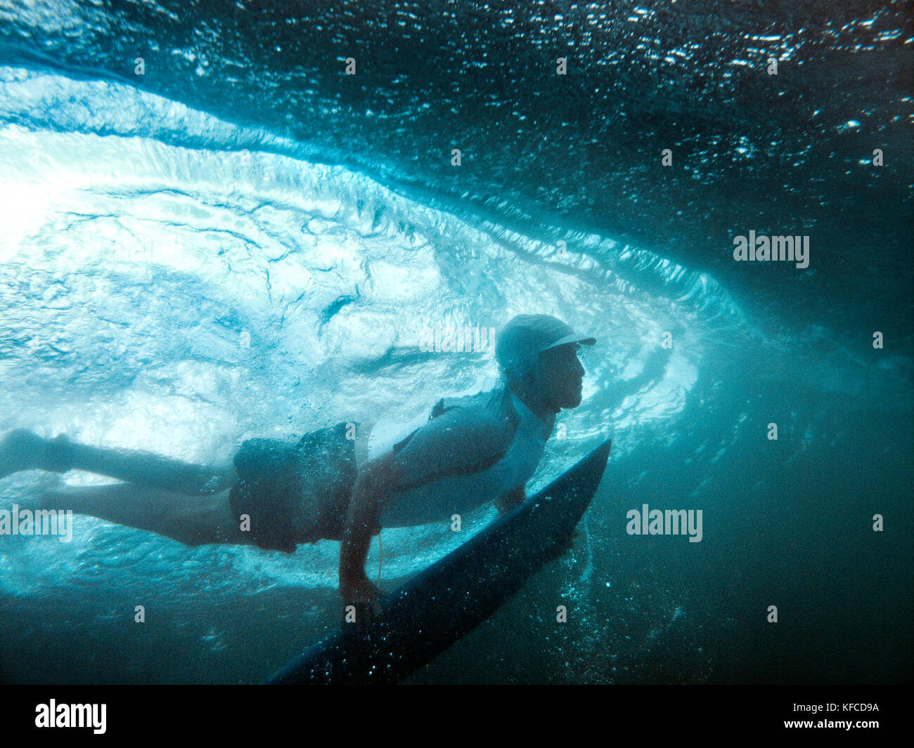 INDONESIA, Mentawai Islands, man duck diving his surfboard under a wave