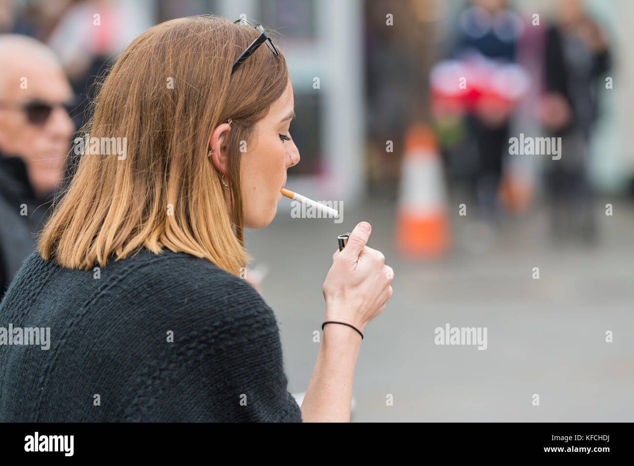 Young Caucasian woman lighting a cigarette in the UK. Unhealthy lifestyle. Stock Photo