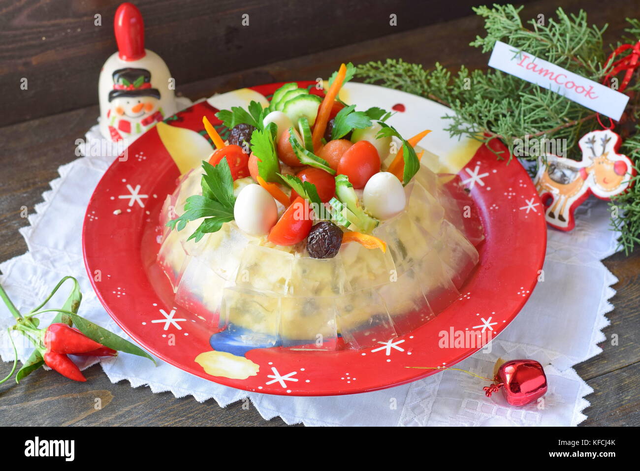 Traditional Russian meat salad with a jelly cubes coat, decorated with quail eggs, cherry