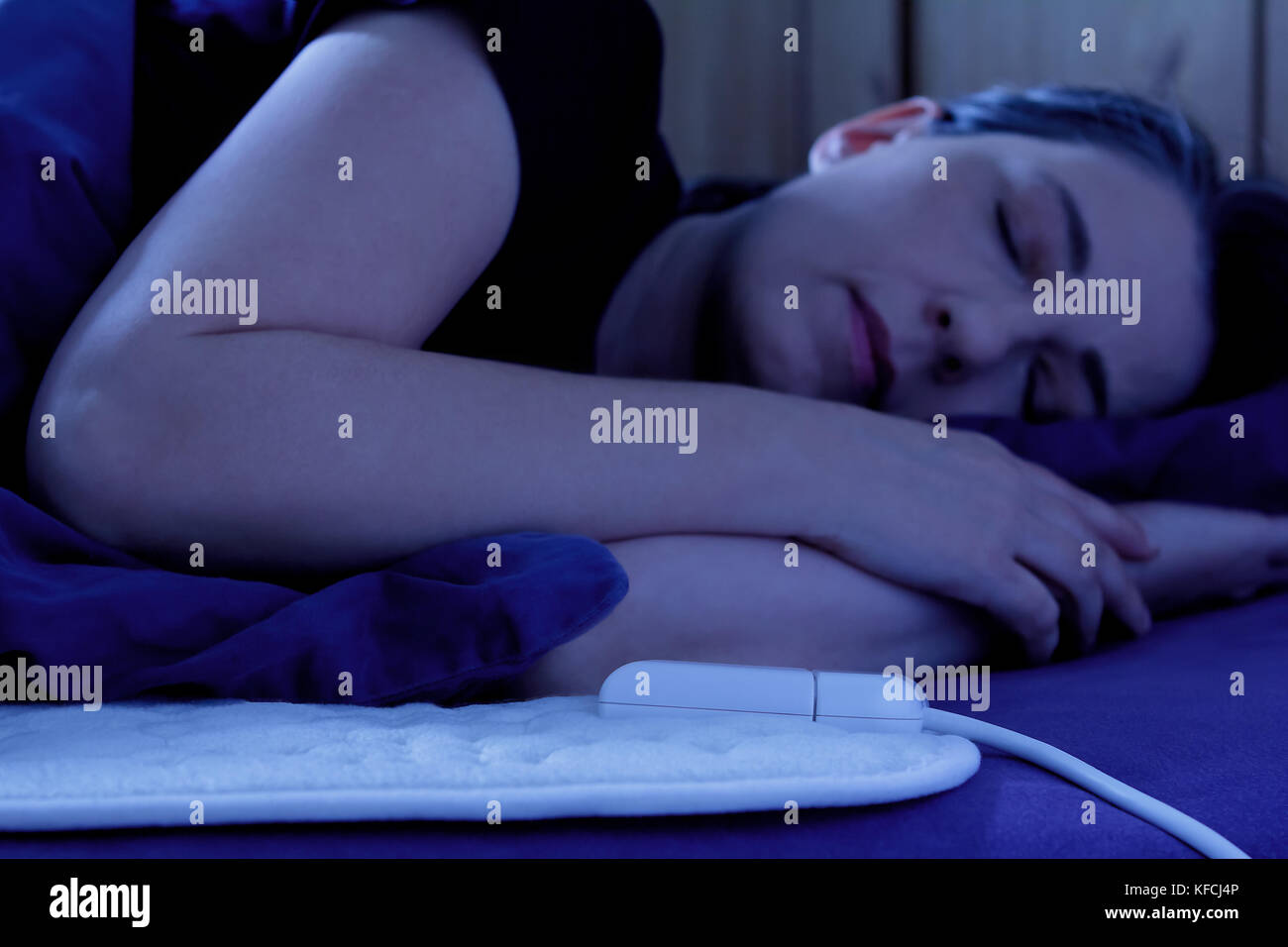 Woman sleeping peacefully on an electric heating blanket in her bed at