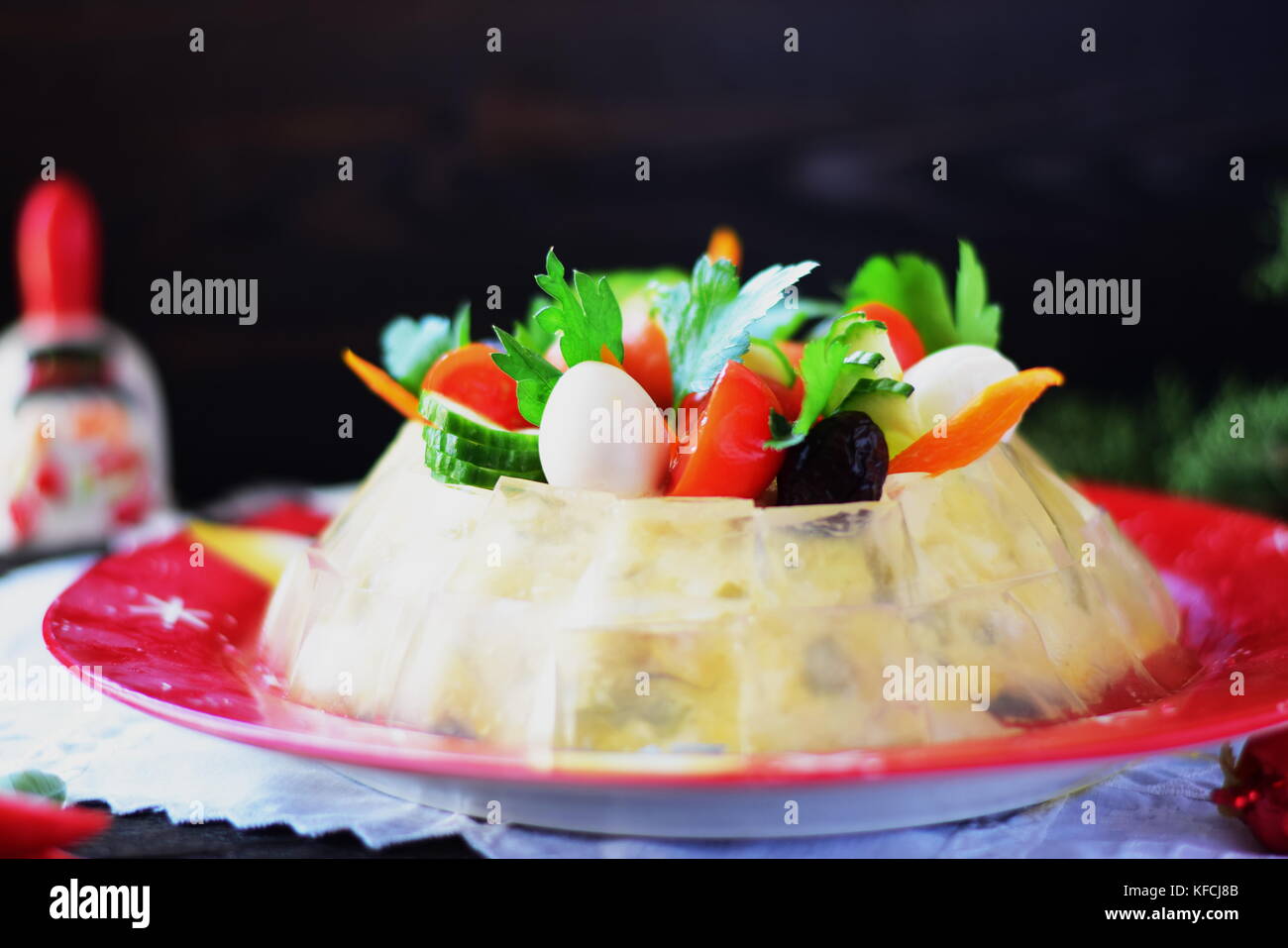 Traditional Russian meat salad with a jelly cubes coat, decorated with quail eggs, cherry