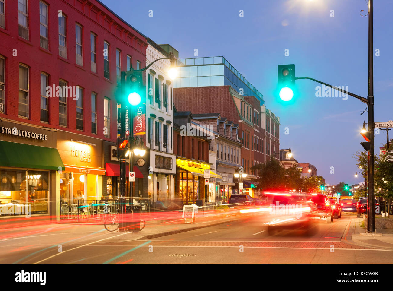 Cars driving by historical buildings along Princess Street at dusk in downtown Kingston, Ontario, Canada. Stock Photo