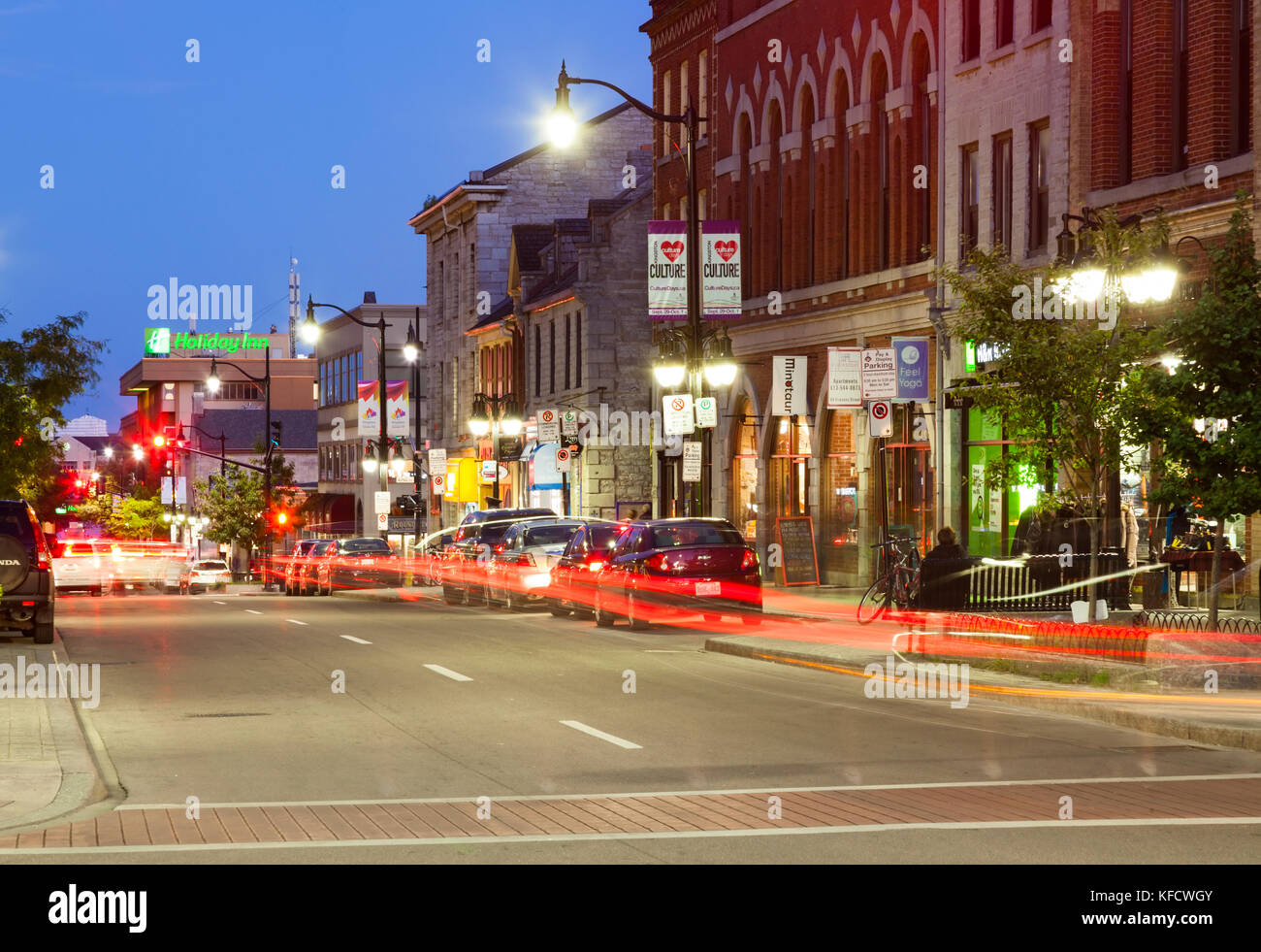 Cars driving by historical buildings along Princess Street at dusk in downtown Kingston, Ontario, Canada. Stock Photo
