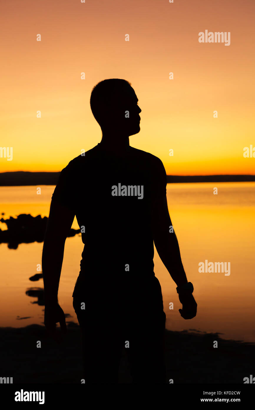 Silhouette of a man standing in the beach at sunset Stock Photo - Alamy