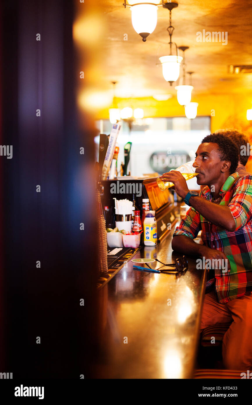 BERMUDA, Hamilton. Chef Marcus Samuelsson watching soccerand  having a beer at Flanagan's Bar in downtown Hamilton. Stock Photo