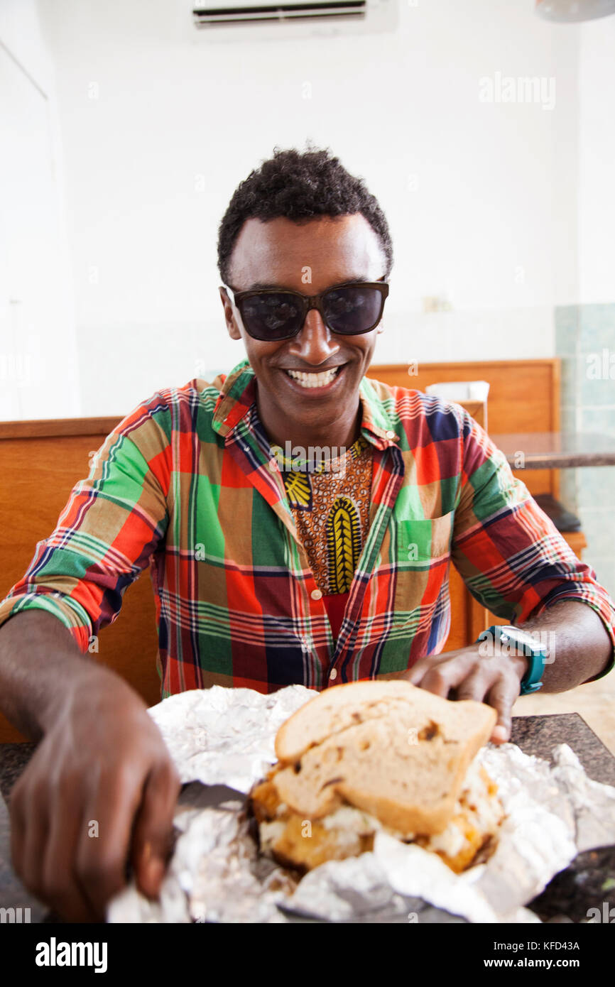 BERMUDA. St. George. Chef Marcus Samuelsson about to eat a fish sandwich at Art Mel's Spicy Dicy Restaurant in St. George. Stock Photo