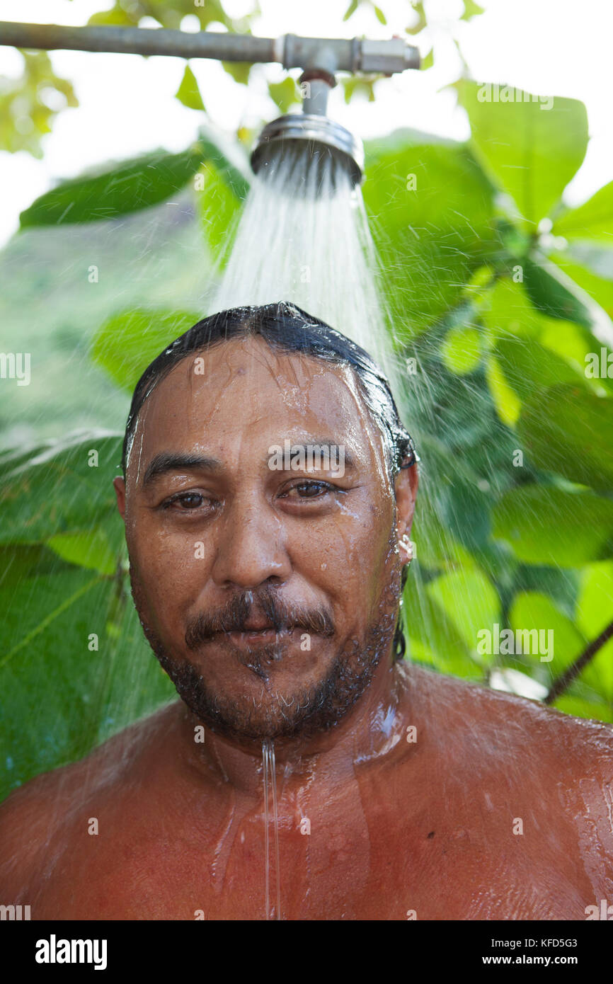FRENCH POLYNESIA, Moorea. Portrait of man showering outside after