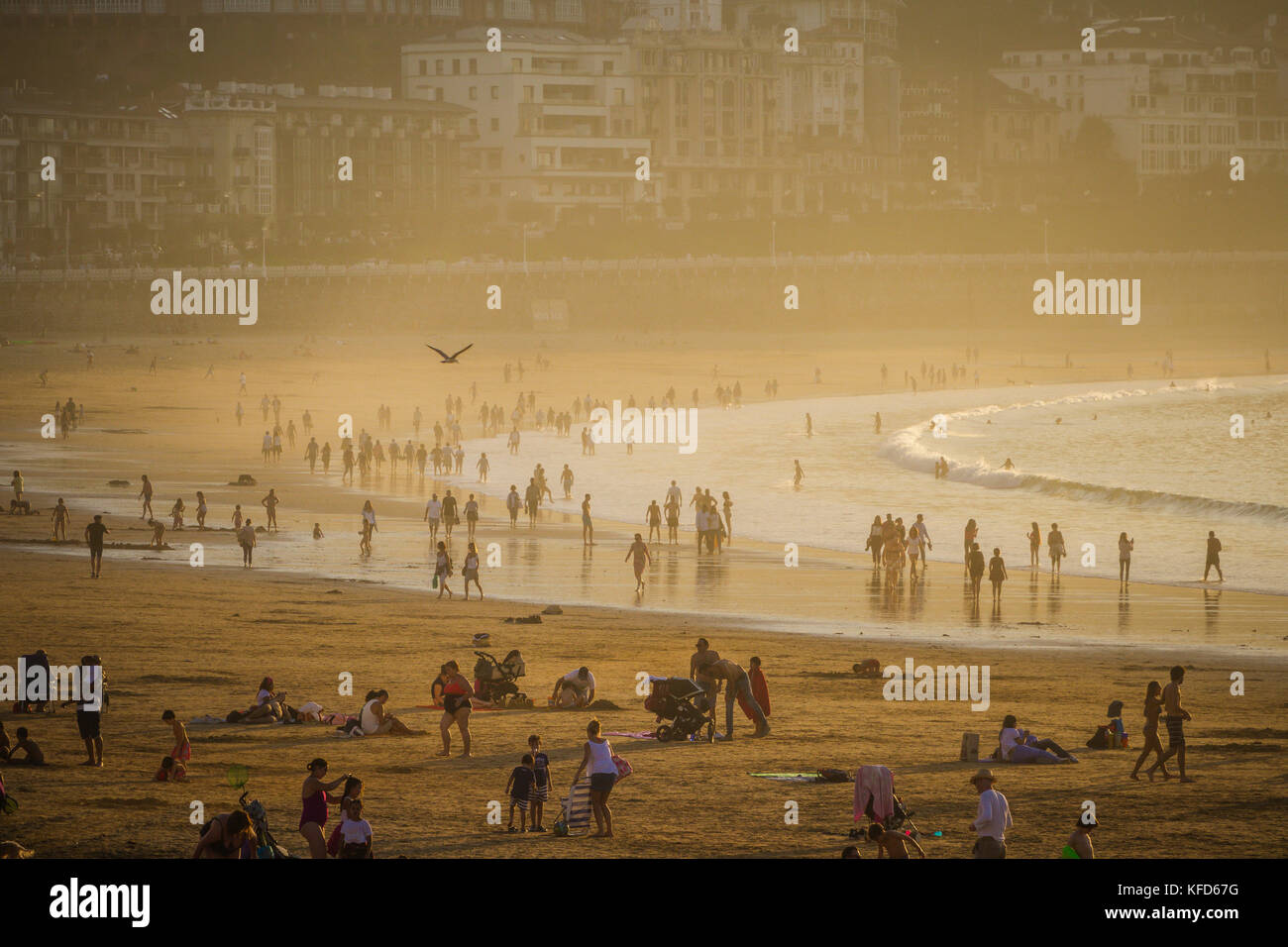 People on the Concha beach enjoying the late afternoon sunshine on a warm October day, San Sebastian, Basque Country, Spain. Stock Photo