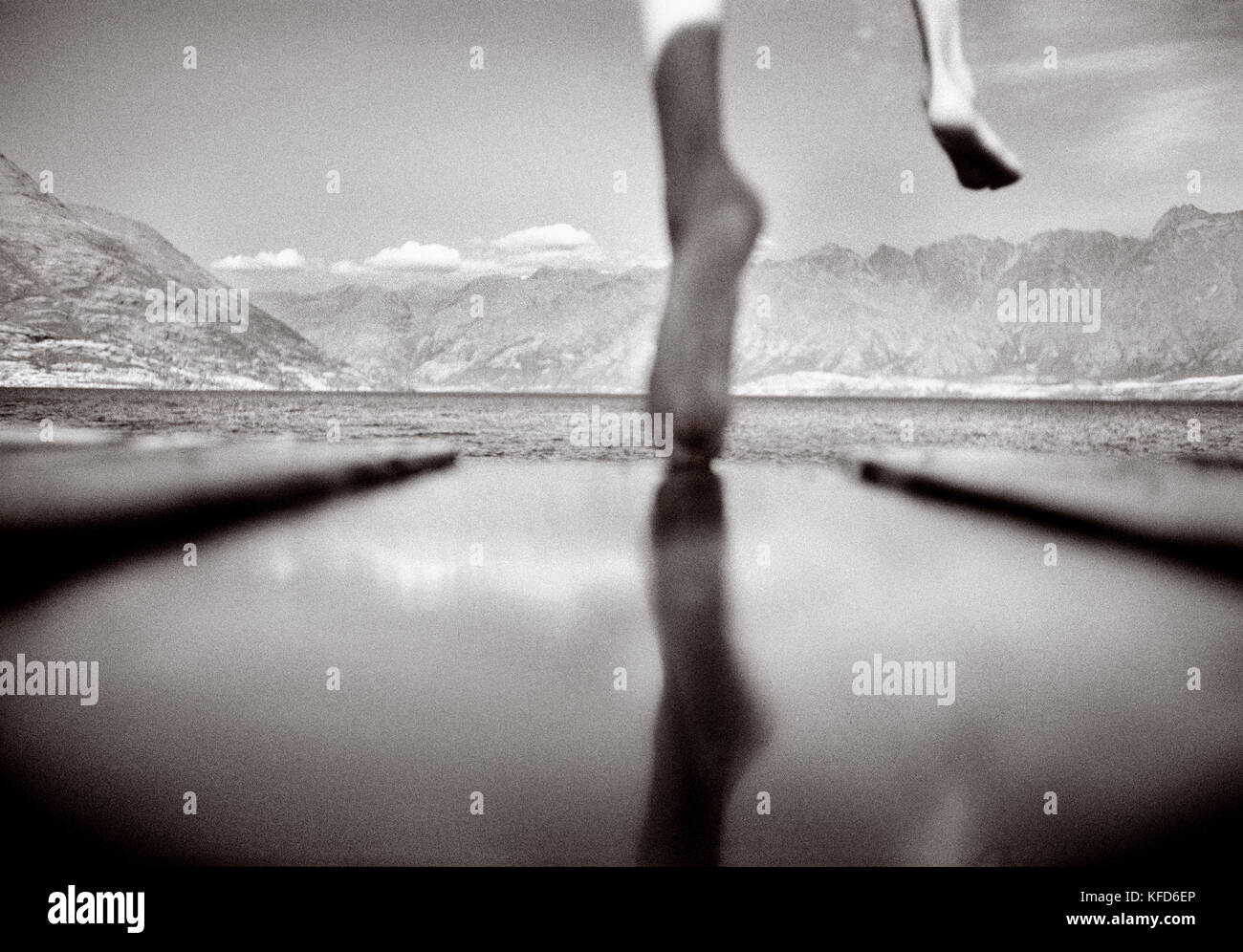 NEW ZEALAND, boy jumping into lake off pier, Lake Waikatipu, Queenstown (B&W) Stock Photo