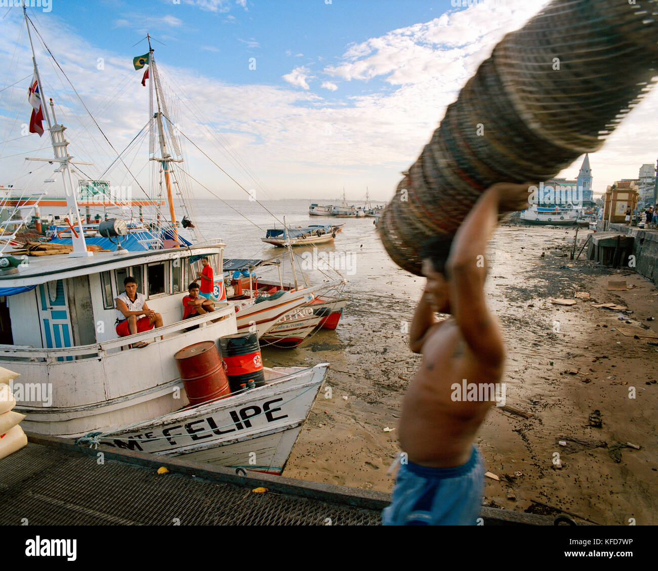 Brazil, Belem, South America, man carrying stack of baskets with fishing boats in the background Stock Photo