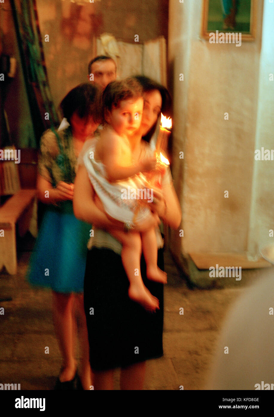 REPUBLIC OF GEORGIA, mother carrying her child and candles at a traditional baptism, Tbilisi Stock Photo