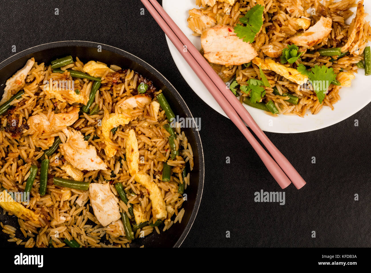 Indonesian Style Nasi Goreng Chicken and Rice Meal Against a Black Background With Chop Sticks Stock Photo