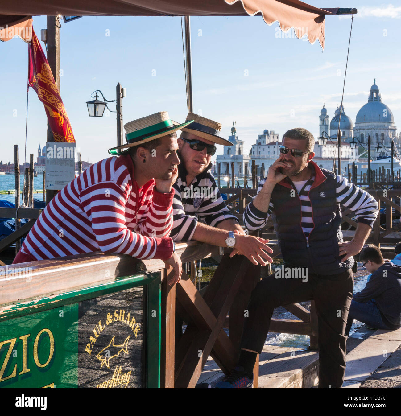 three gondoliers VENICE ITALY VENICE Three gondoliers in traditional shirts waiting at gondola hire station on the Grand canal Venice Italy EU Europe Stock Photo