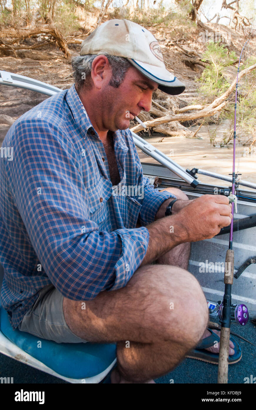 Local resident at Windorah, southwestern Queensland, prepares his rod for fishing at a waterhole in Cooper Creek Stock Photo