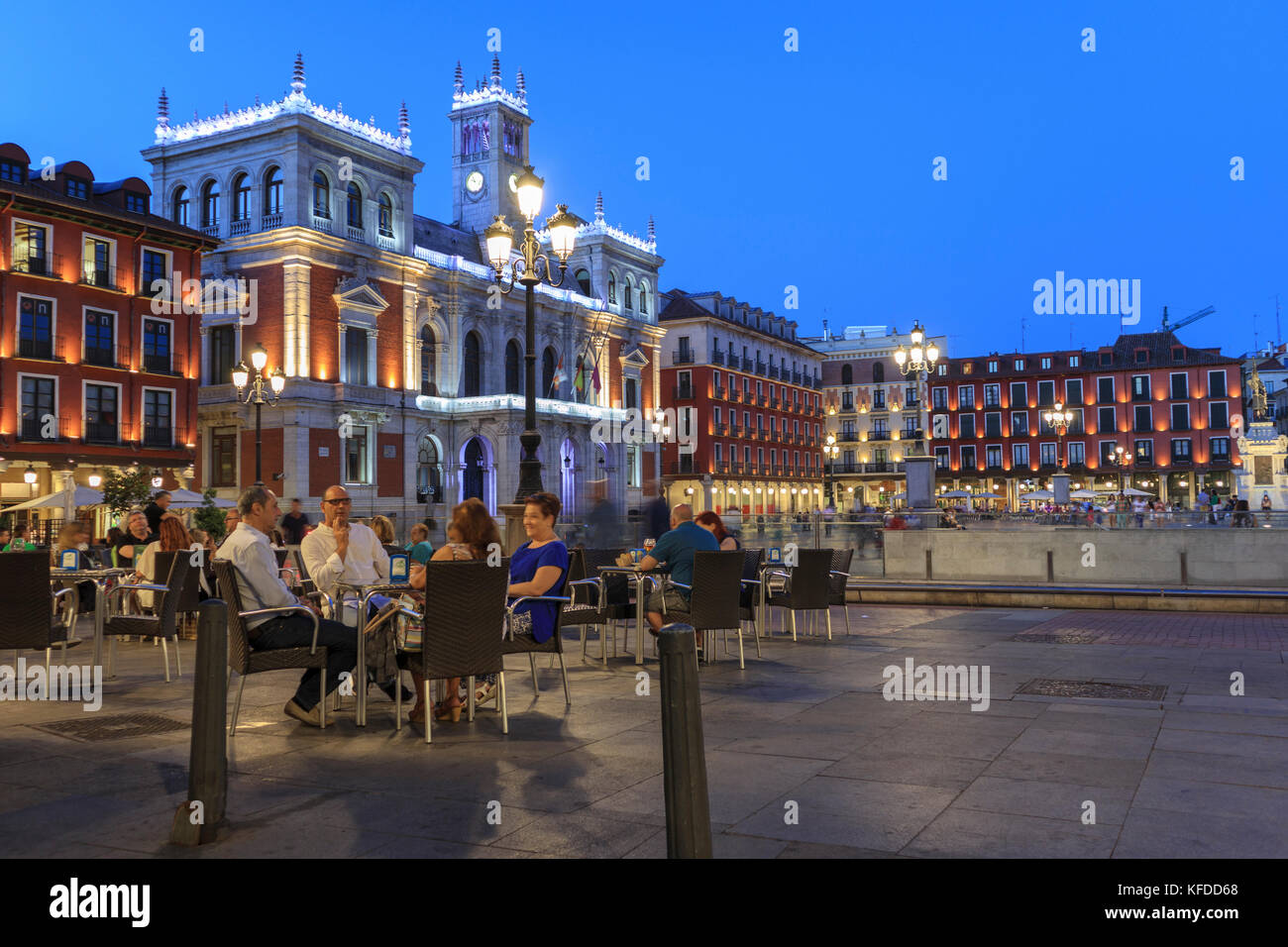 Groups sitting at outside tables enjoying the evening on the Plaza Mayor Valladolid Spain. Floodlit Townhall in the background Stock Photo