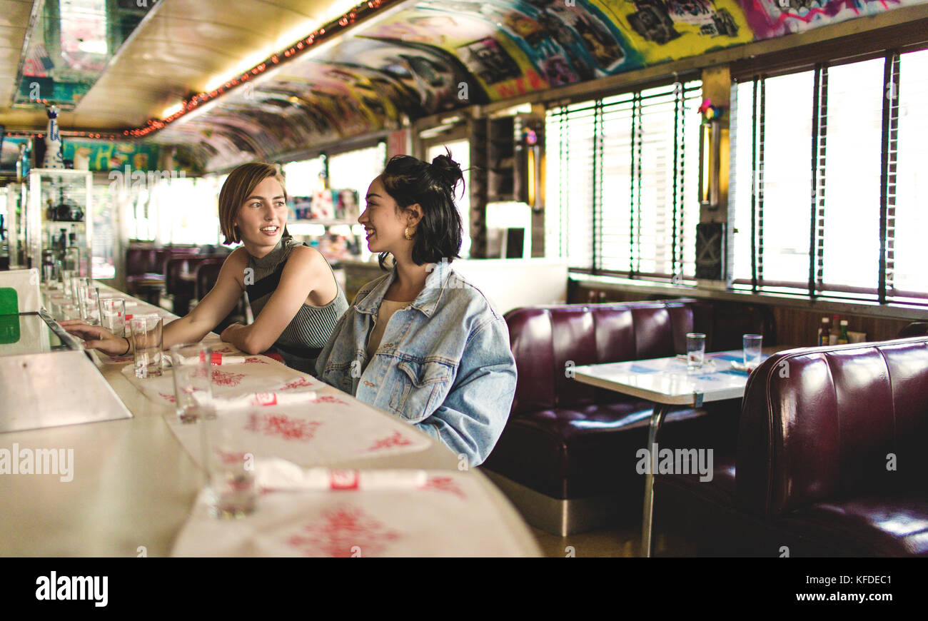 Two Young Women Sitting Side By Side At A Bar Counter In A Diner Stock   Two Young Women Sitting Side By Side At A Bar Counter In A Diner KFDEC1 