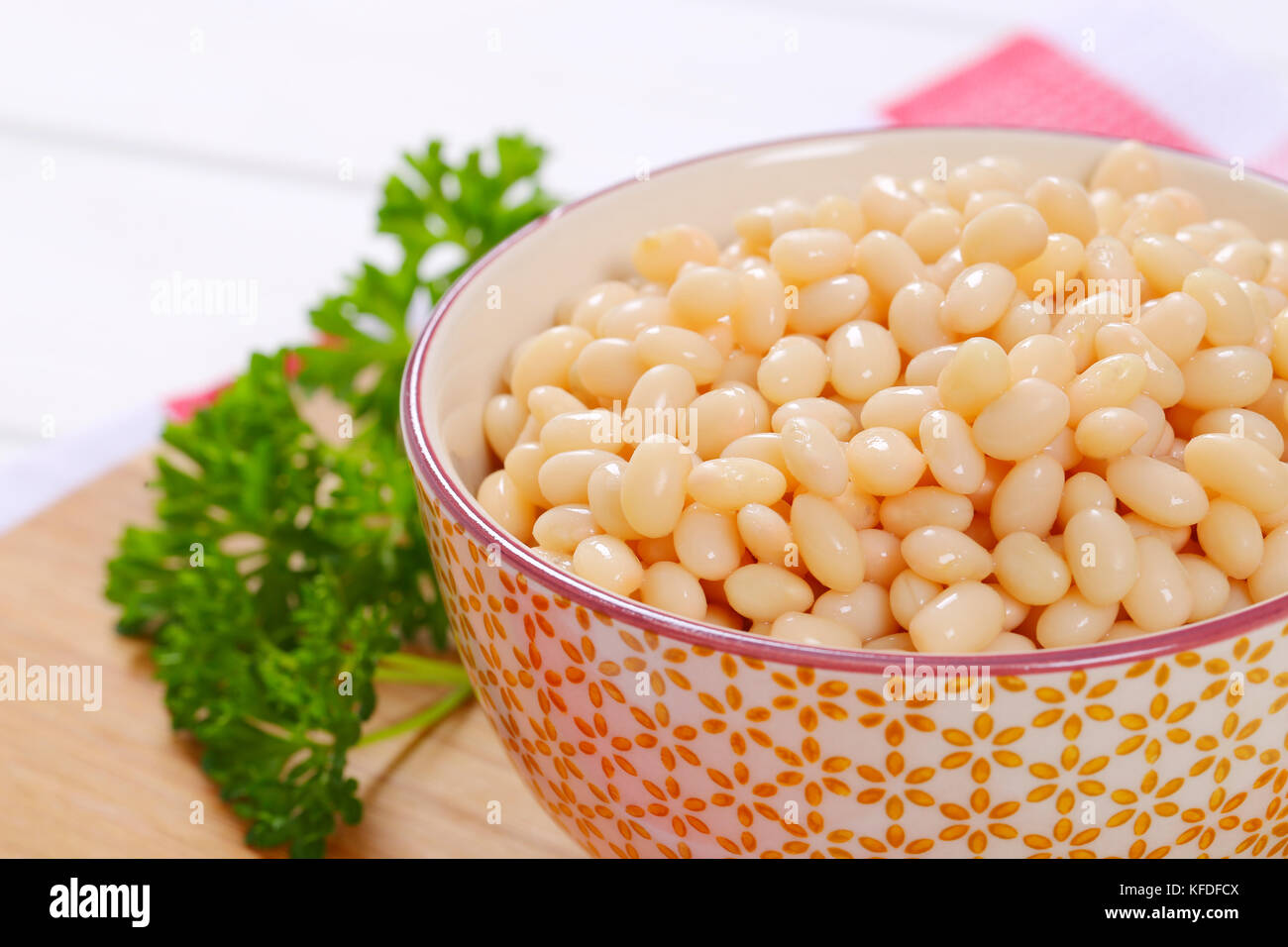 bowl of canned white beans on wooden cutting board - close up Stock Photo