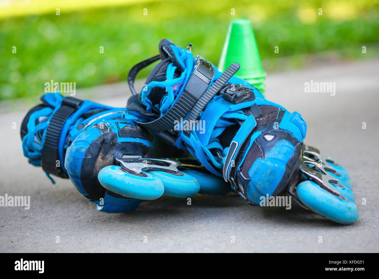 Close up of blue roller skates with slalom cones lying on asphalt Stock
