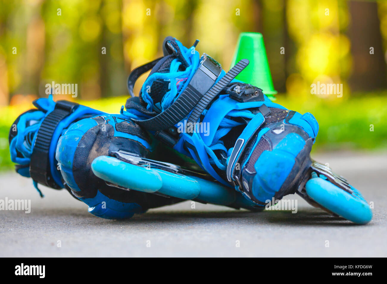 Close up of blue roller skates with slalom cones lying on asphalt Stock