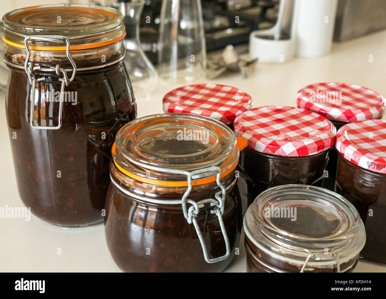 Variety of sizes of jam jars and glass Kilner jars filled with homemade  chutney on a white kitchen counter, United kingdom Stock Photo