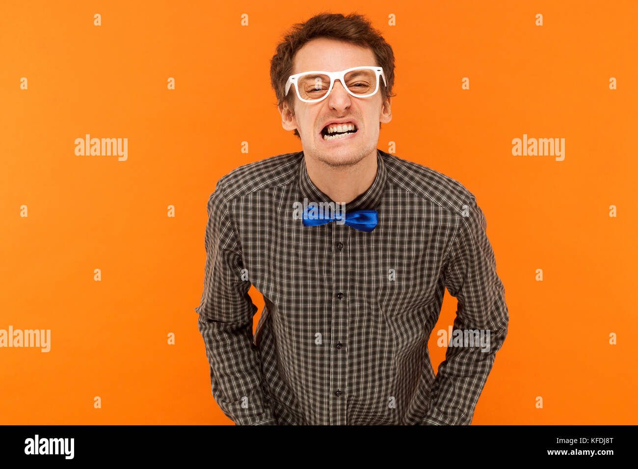 Anger stupid man looking at camera and showing funny face. Studio shot. Isolated on orange background Stock Photo